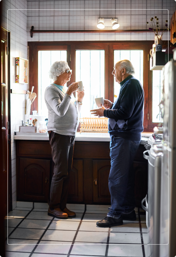 elderly couple standing in kitchen chatting