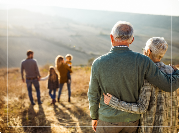 elderly couple embracing watching their children and grandchildren