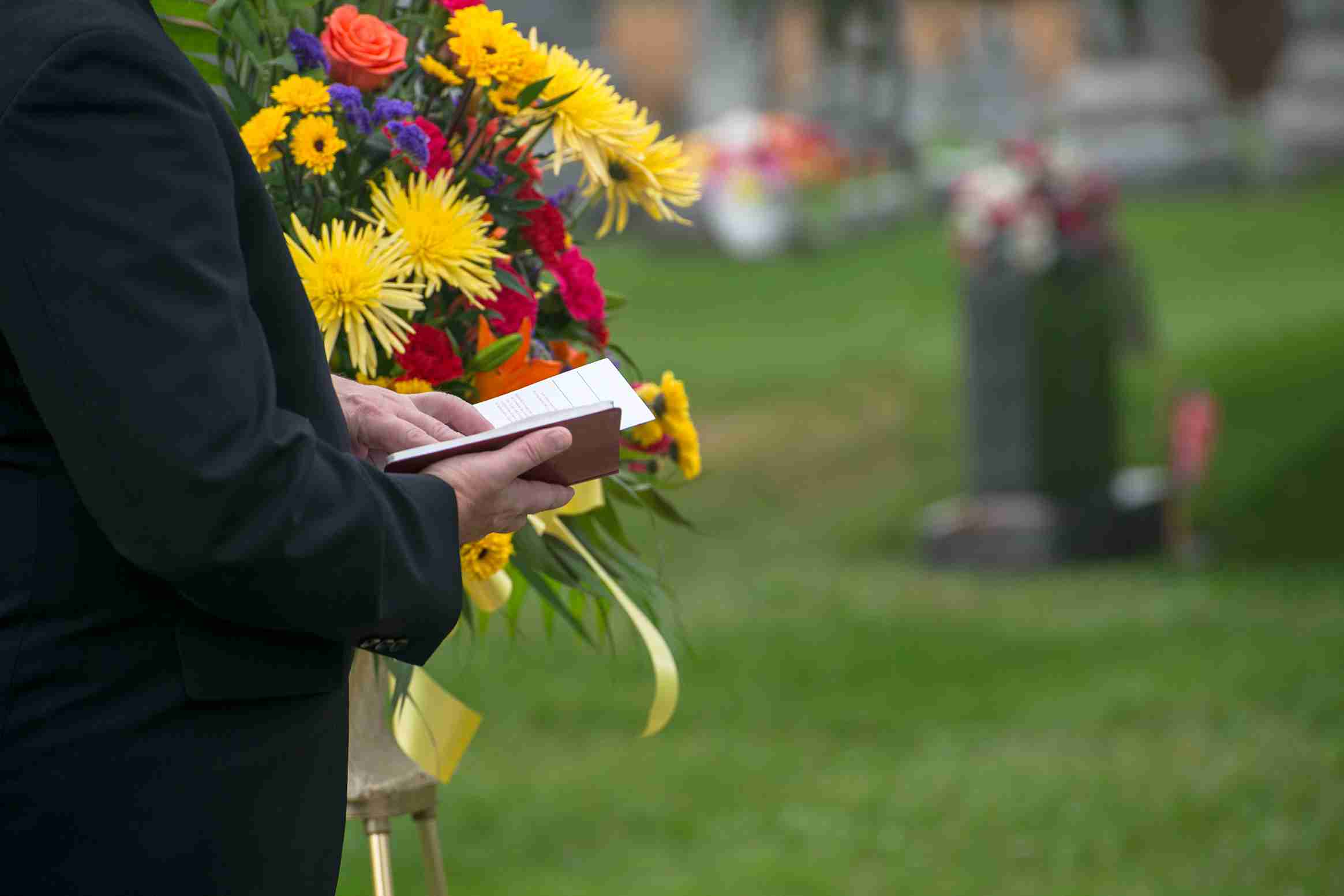 direct cremation vs traditional cremation - A Pastor Or Minister Reads From The Bible During A Funeral