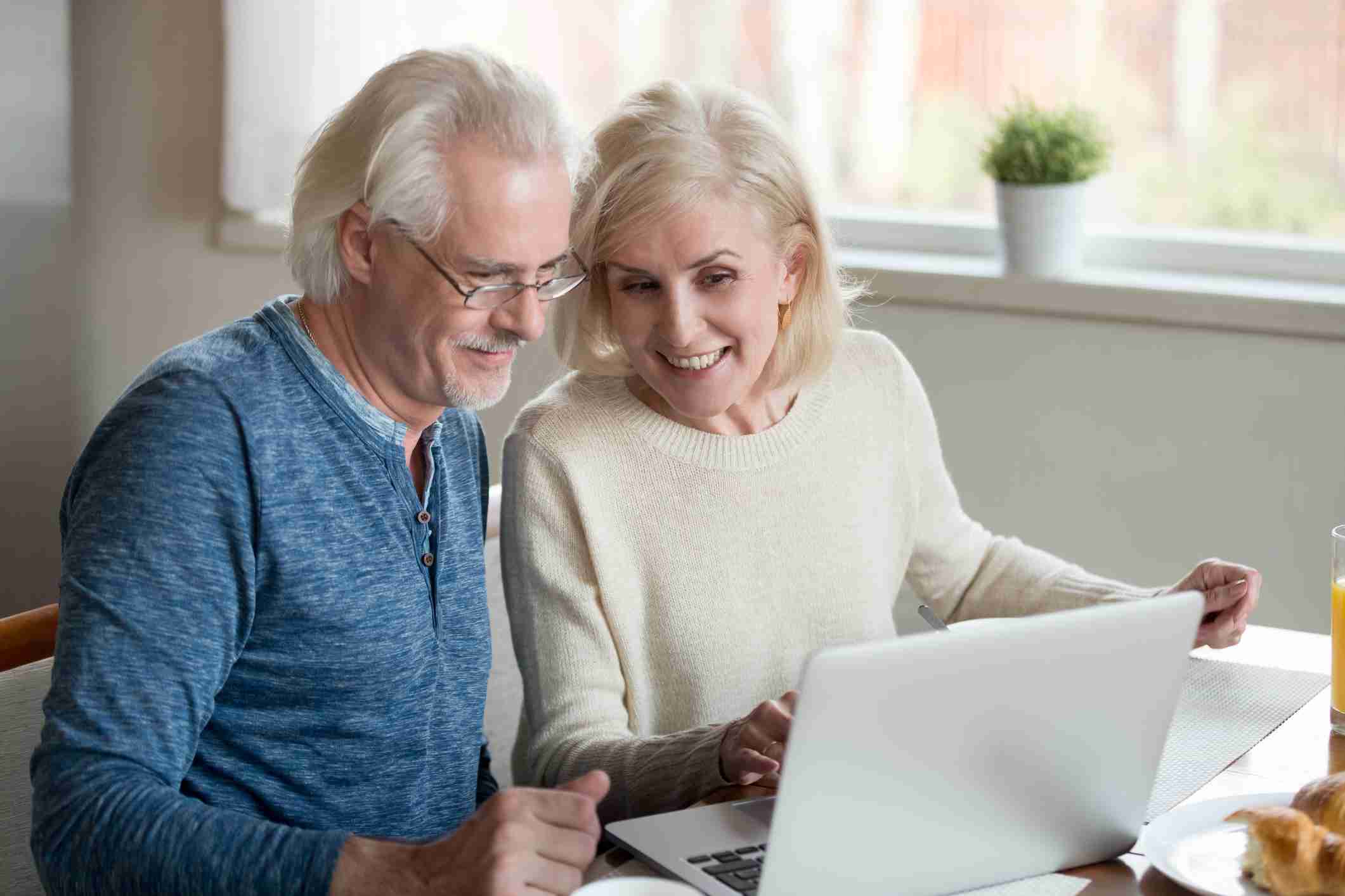family planning a direct cremation - Happy Older Family Couple Talking Using Laptop Having Breakfast.