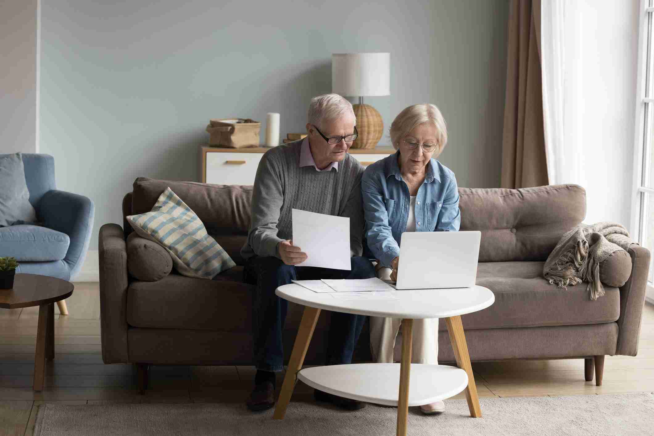 older couple getting direct cremation quotes - Focused Couple Of Older Senior Pensioners Checking Domestic Financial Papers